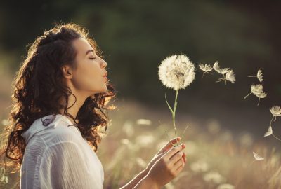 Beautiful,Young,Woman,Sitting,On,The,Field,In,Green,Grass